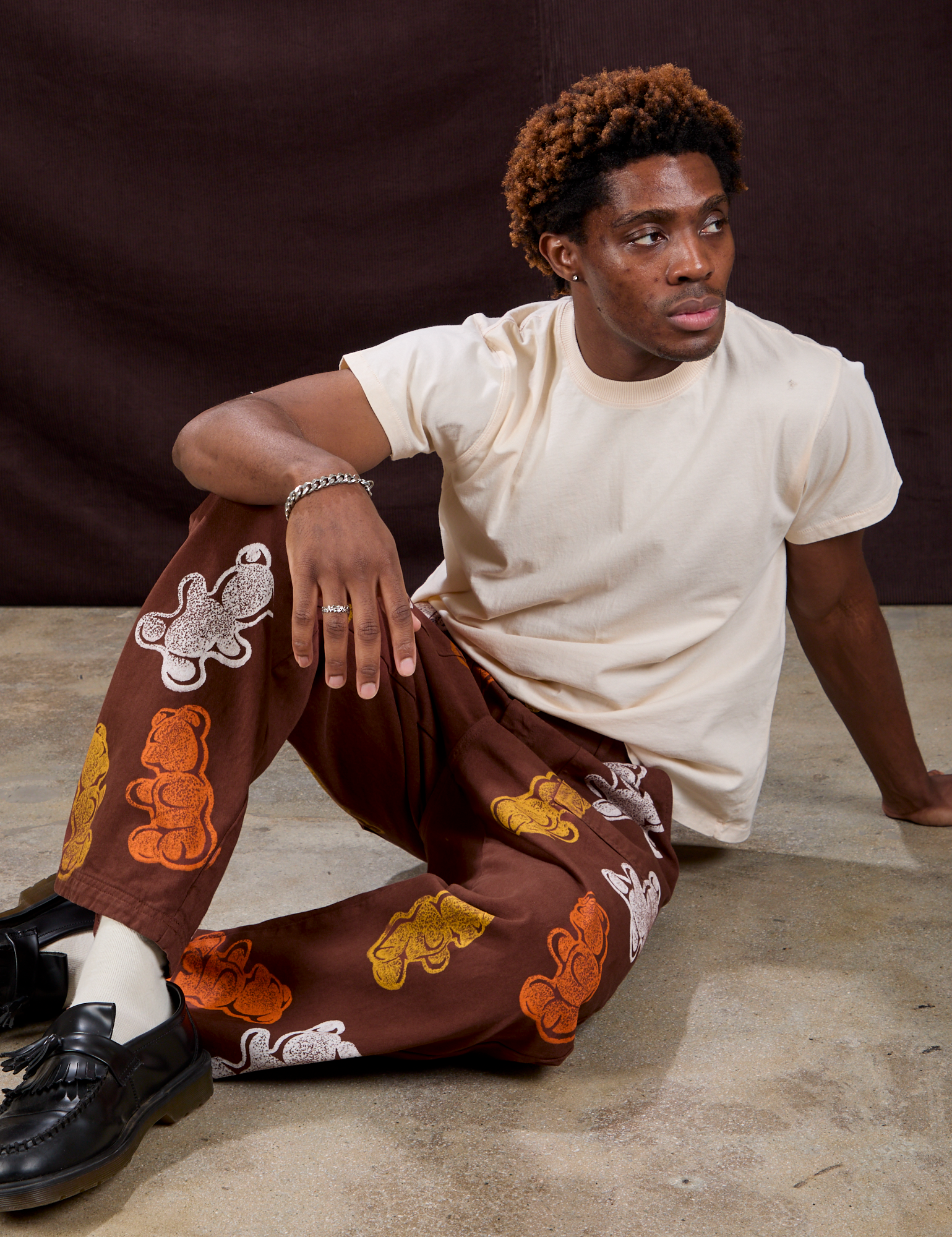 Isaac is wearing Gummy Bear Paintstamped Work Pants in Fudgesicle Brown and Organic Vintage Tee in Vintage Off-White
