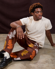Isaac is wearing Gummy Bear Paintstamped Work Pants in Fudgesicle Brown and Organic Vintage Tee in Vintage Off-White