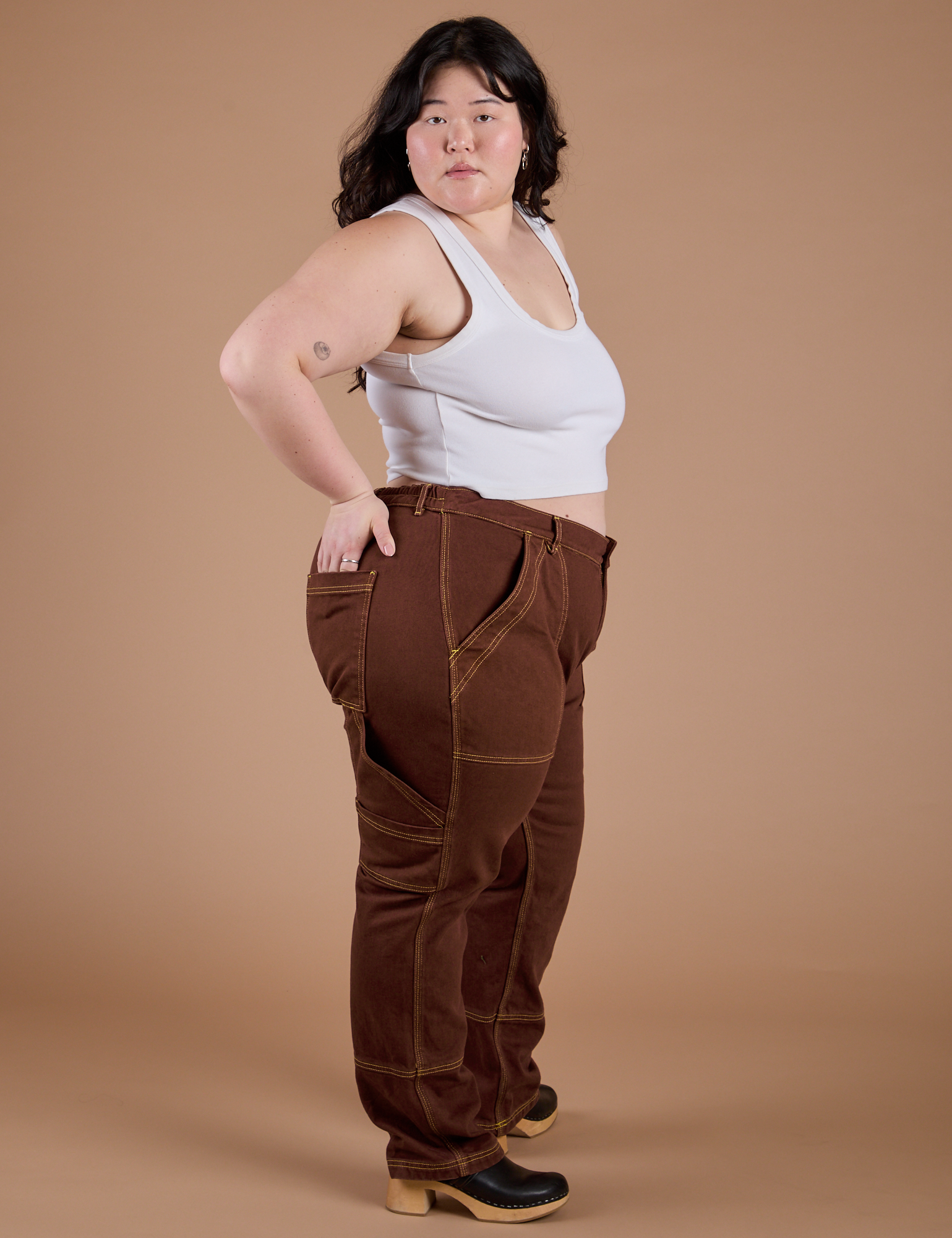 Side view of Carpenter Jeans in Fudgesicle Brown and Cropped Tank in Vintage Tee White on Ashley