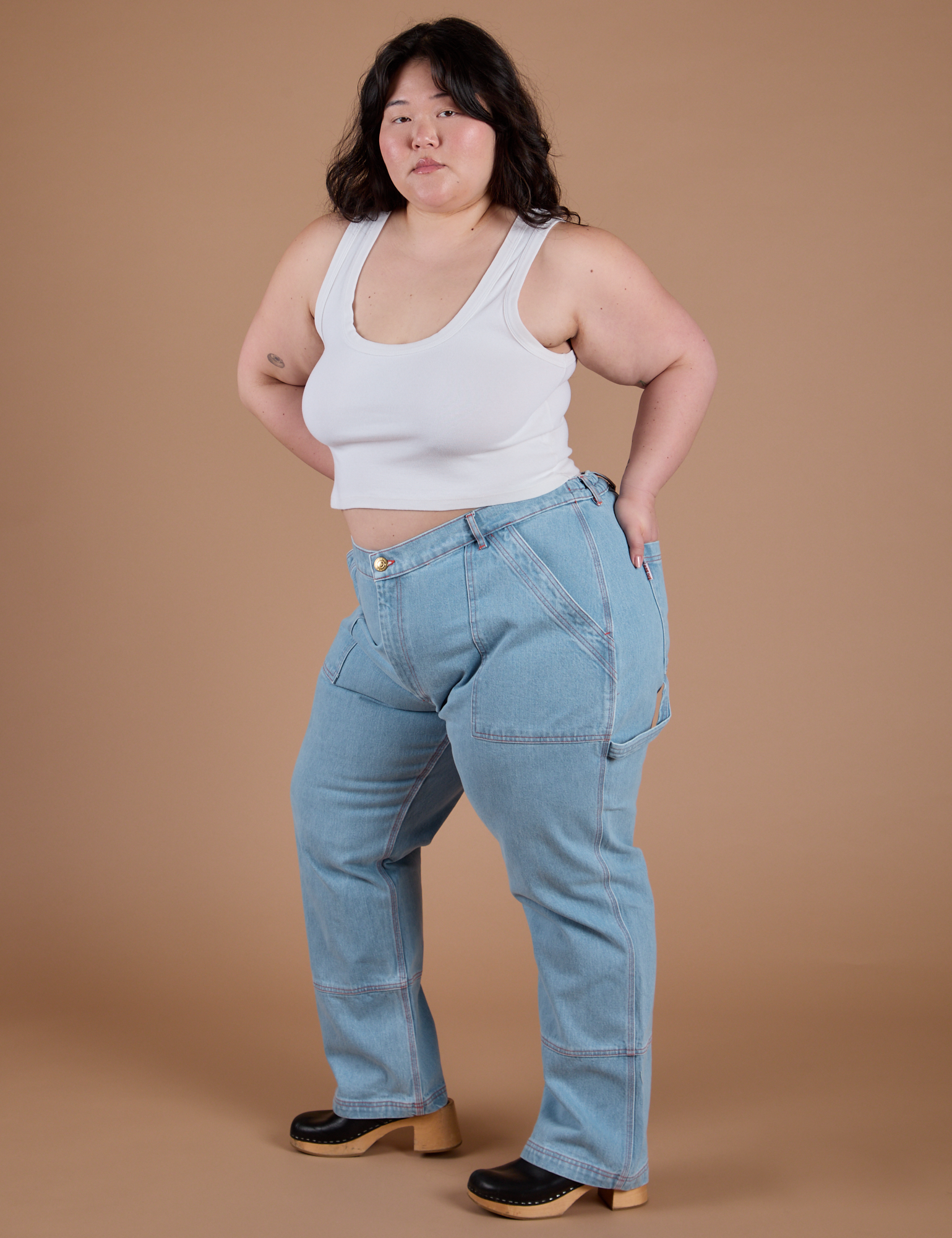 Angled front view of Carpenter Jeans in Light Wash and Cropped Tank in Vintage Tee White on Ashley