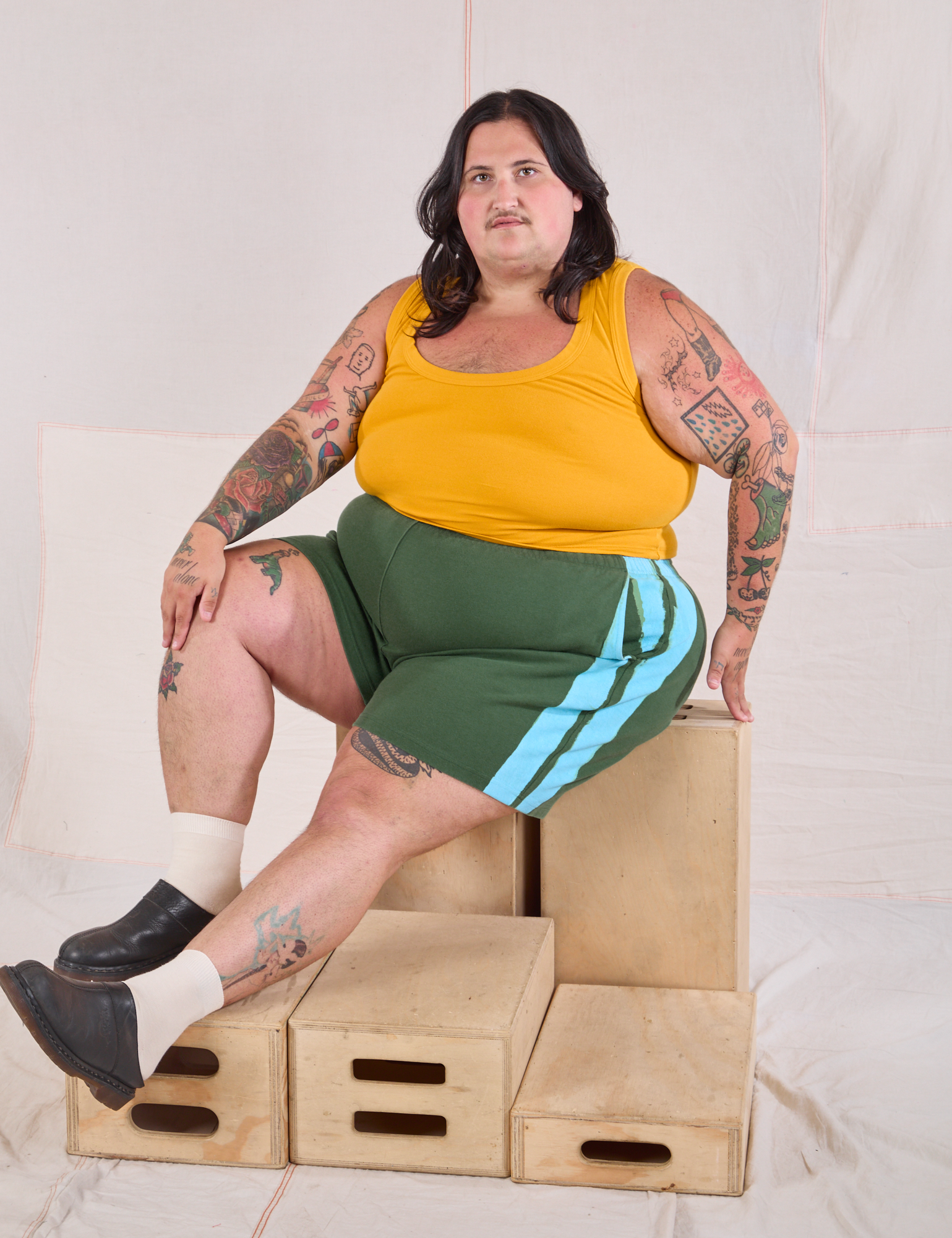 Sam is wearing Painted Stripe Easy Shorts in Dark Emerald Green and golden yellow Cropped Tank
