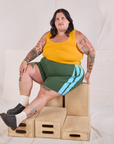 Sam is wearing Painted Stripe Easy Shorts in Dark Emerald Green and golden yellow Cropped Tank