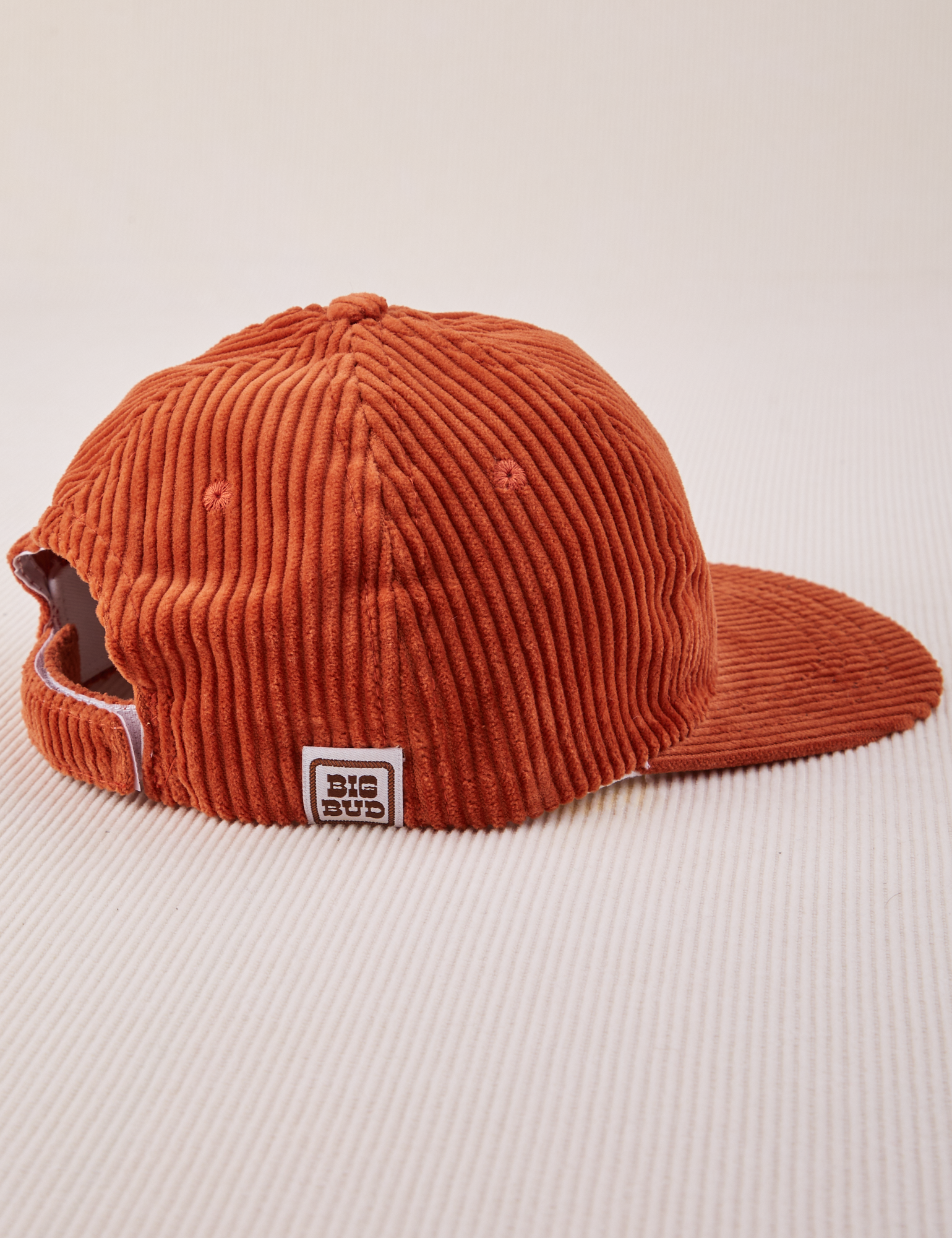 Side view of Dugout Corduroy Hat in Burnt Terracotta. Big Bud label sewn on edge of hat.
