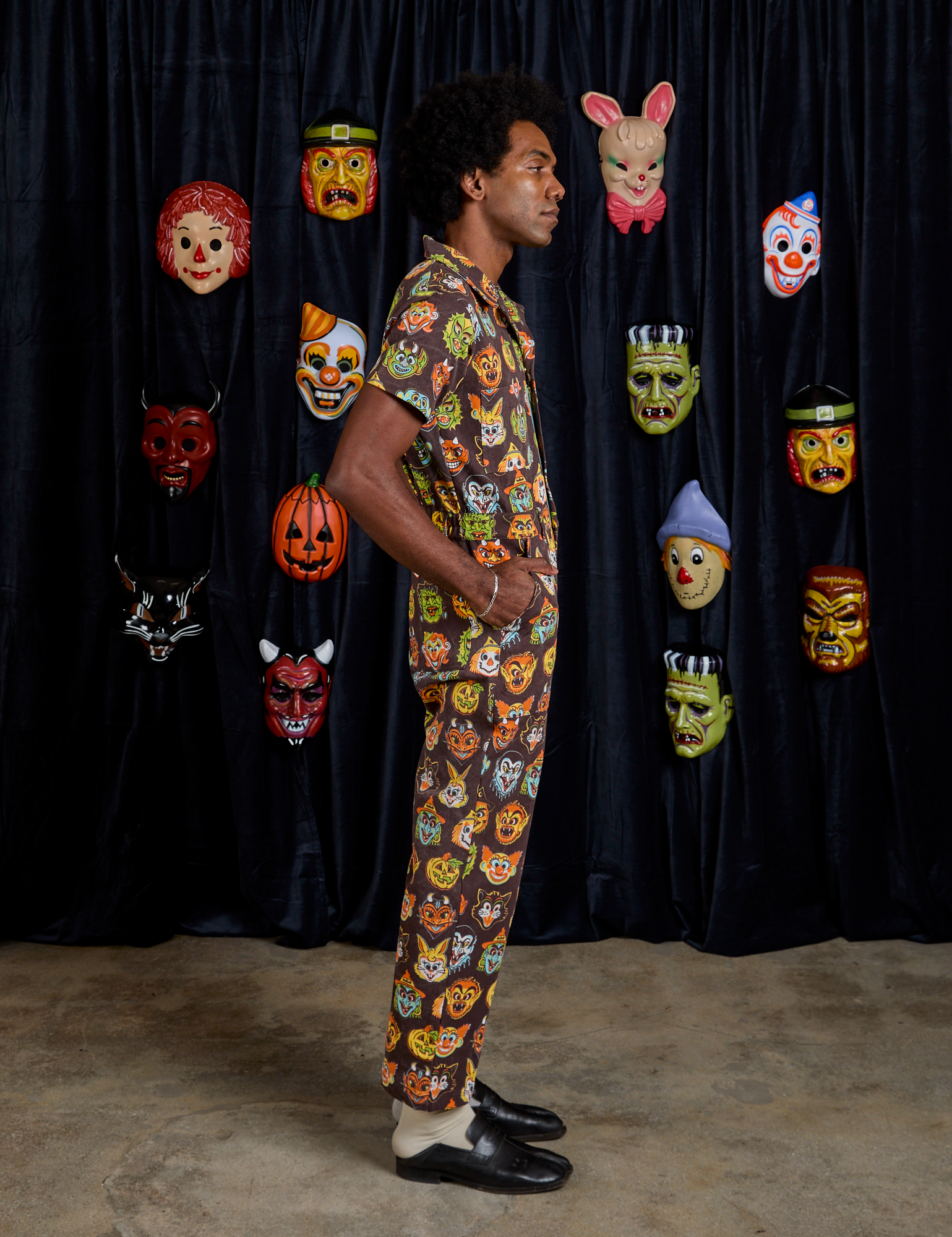 Side view of Short Sleeve Jumpsuit in Halloween Masks on Jerrod