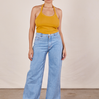 Tiara is wearing Halter Top in Mustard Yellow and light wash Sailor Jeans