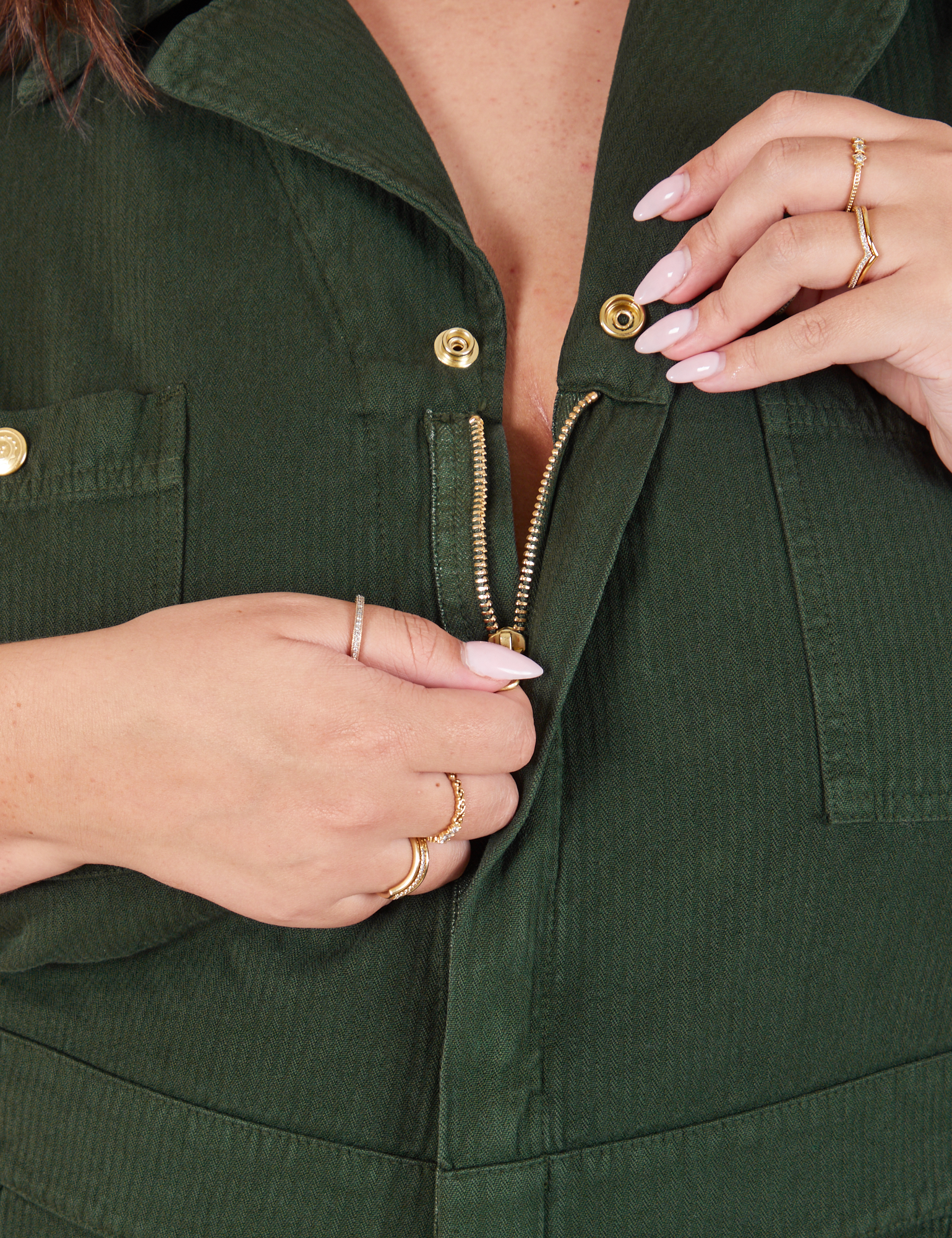 Heritage Short Sleeve Jumpsuit in Swamp Green front close up. Katie is pulling down the zipper tab