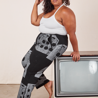 Side view of Icon Work Pants in Dice and vintage off-white Halter Top. Morgan is sitting at the edge of a vintage tv.