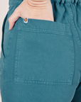 Back pocket close up of Short Sleeve Jumpsuit in Marine Blue. Alex has her hand in the pocket.