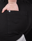 Column Work Pants in Basic Black back pocket close up. Ashley has her hand in the pocket.