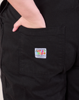 Original Overalls in Mono Black back pocket close up. Marielena has her hand in the pocket.