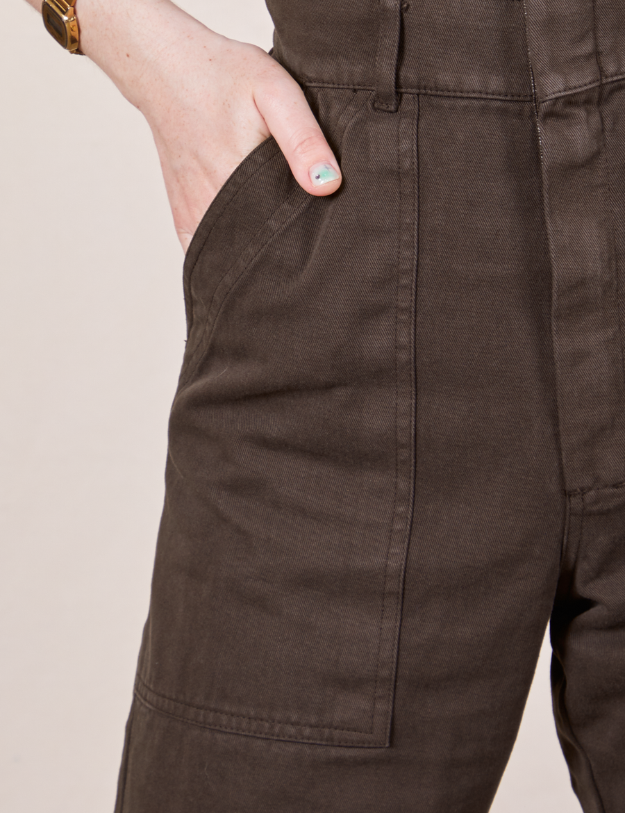 Front pocket close up of Petite Short Sleeve Jumpsuit in Espresso Brown. Worn by Hana with her hand in the pocket.