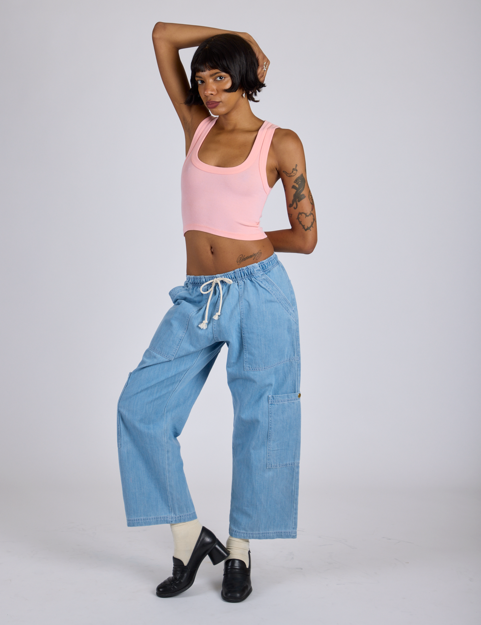 Kira is wearing Cropped Tank Top in Baby Pink and light wash Denim Drop Pocket Pants