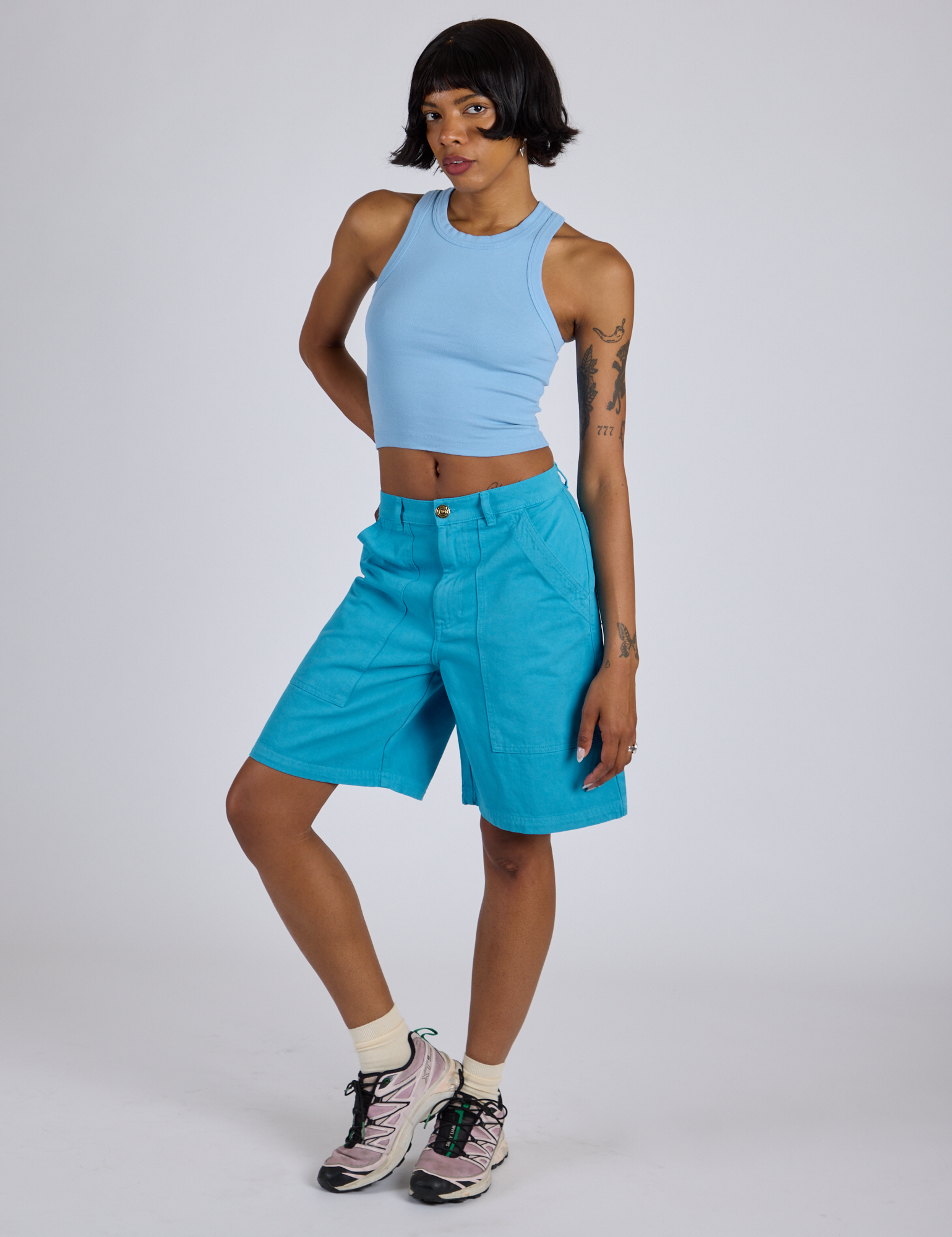 Kira is 5’10” and wearing XS Longline Work Shorts in Hawaiian Blue paired with a baby blue Racerback Tank