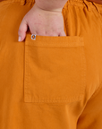 Close up of Juliet's hand in the back pocket of Longline Work Shorts in Creamsicle Orange