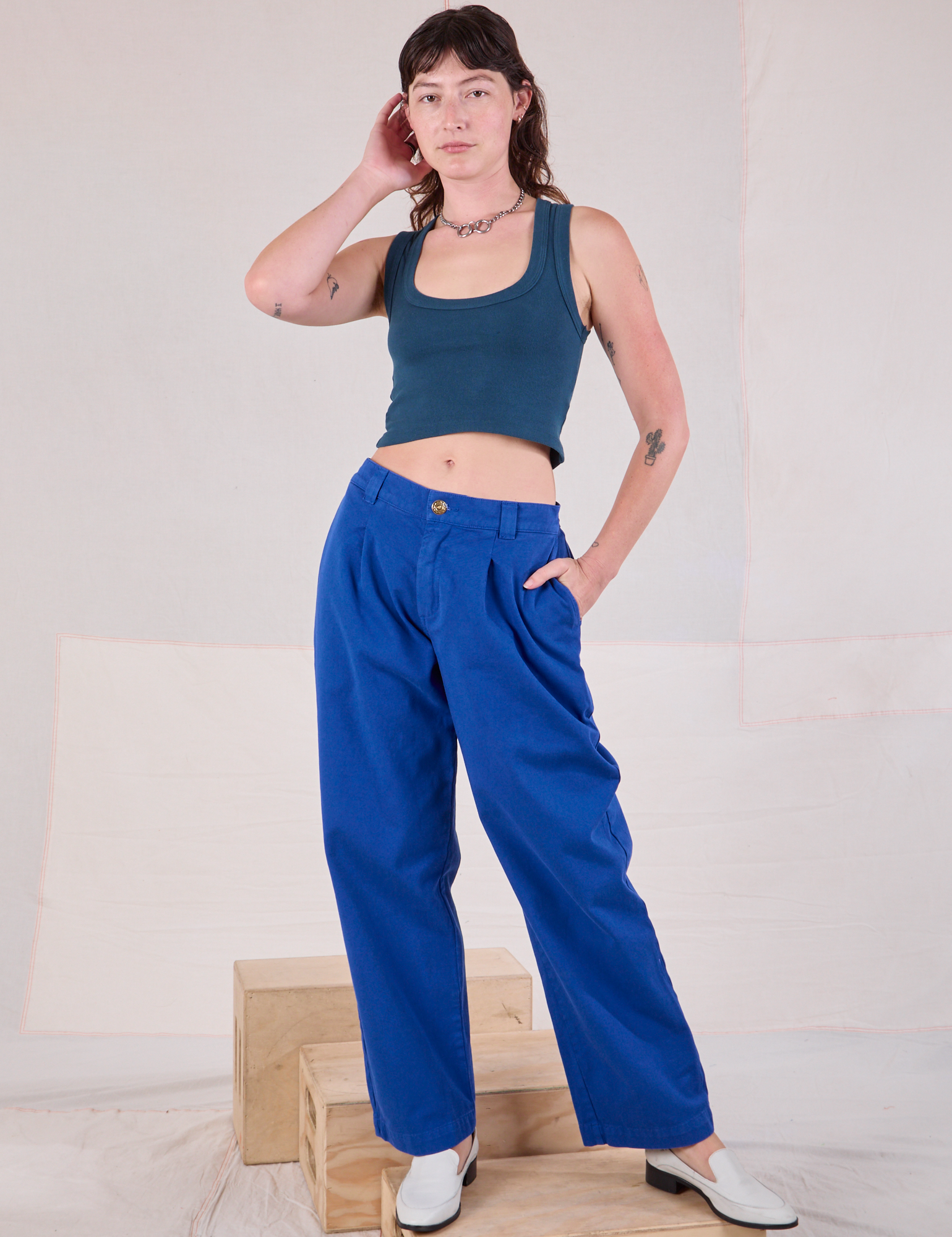 Alex is wearing Mid-Rise Pleated Trousers in Royal Blue and lagoon Cropped Tank