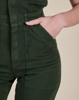 Close up of Alex's hand in the front pocket of Short Sleeve Jumpsuit in Swamp Green