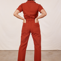 Back view of Short Sleeve Jumpsuit in Paprika. Tiara has both hands in the back pockets.