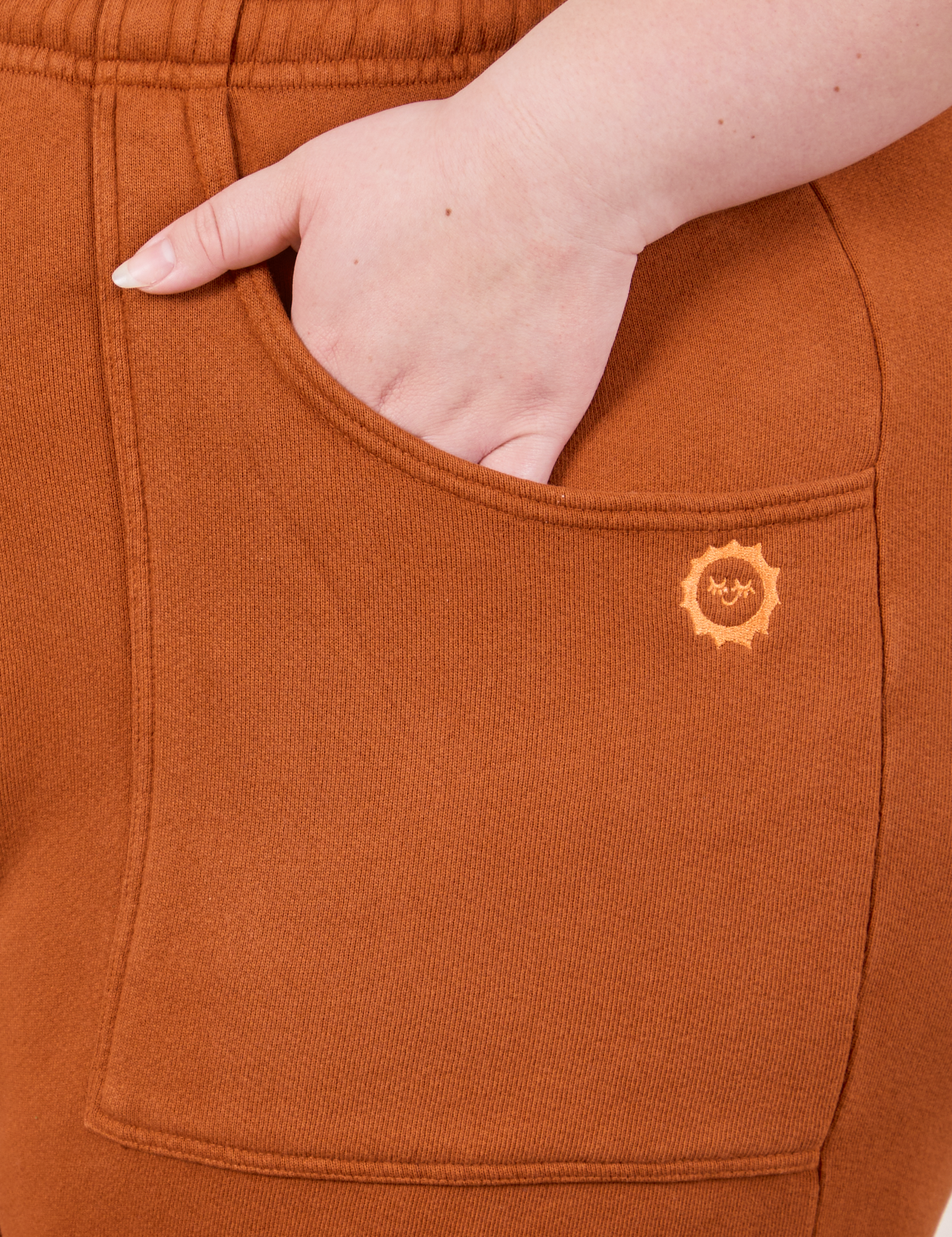 Cropped Rolled Cuff Sweatpants in Burnt Terracotta front pocket close up. Ashley has her hand in the pocket.
