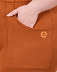 Cropped Rolled Cuff Sweatpants in Burnt Terracotta front pocket close up. Ashley has her hand in the pocket.