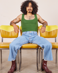 Jesse is wearing Cropped Tank Top in Lawn Green and light wash Sailor Jeans. They are sitting on a yellow chair.