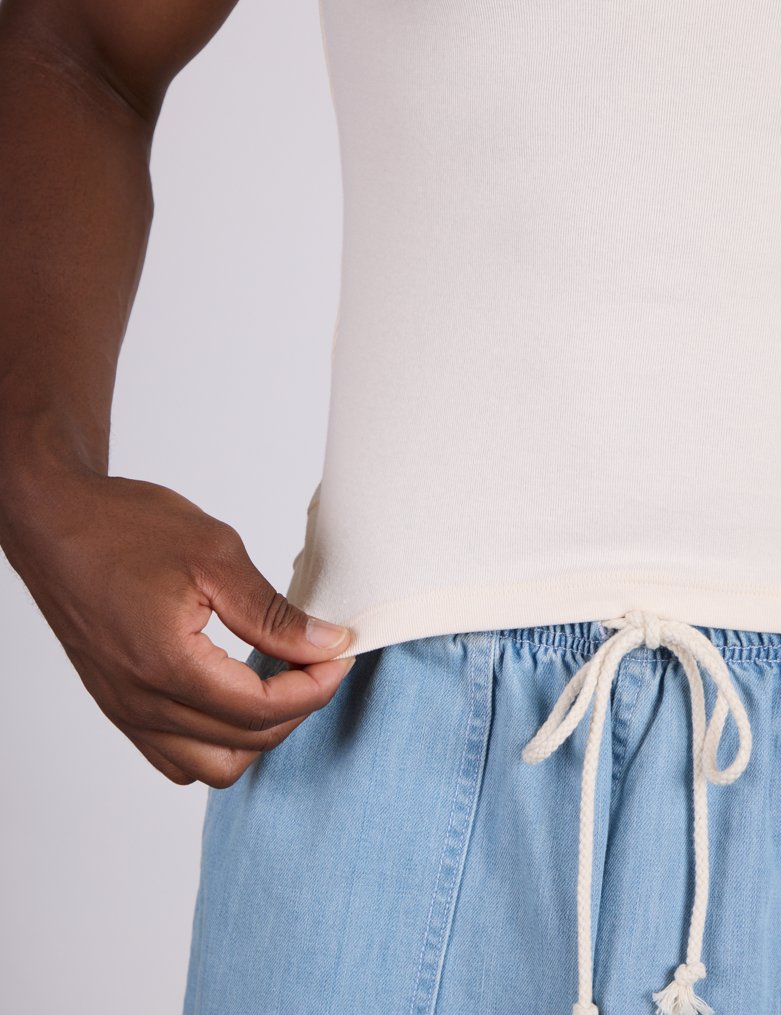 Close up of Isaac holding The Tank Top in Vintage Tee Off-White bottom hem