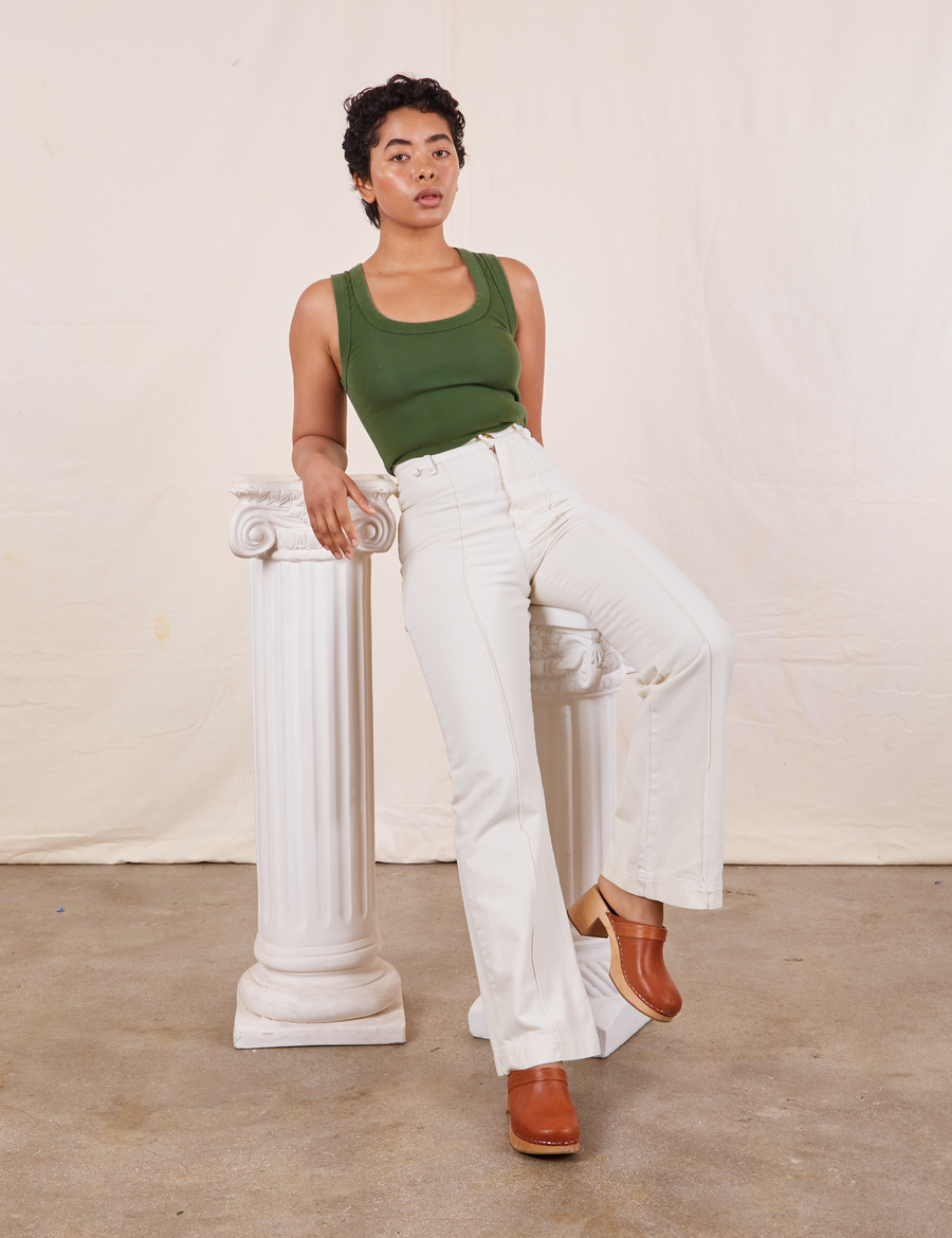 Tank Top in Dark Emerald Green on Mika wearing vintage off-white Western Pants sitting on a white column