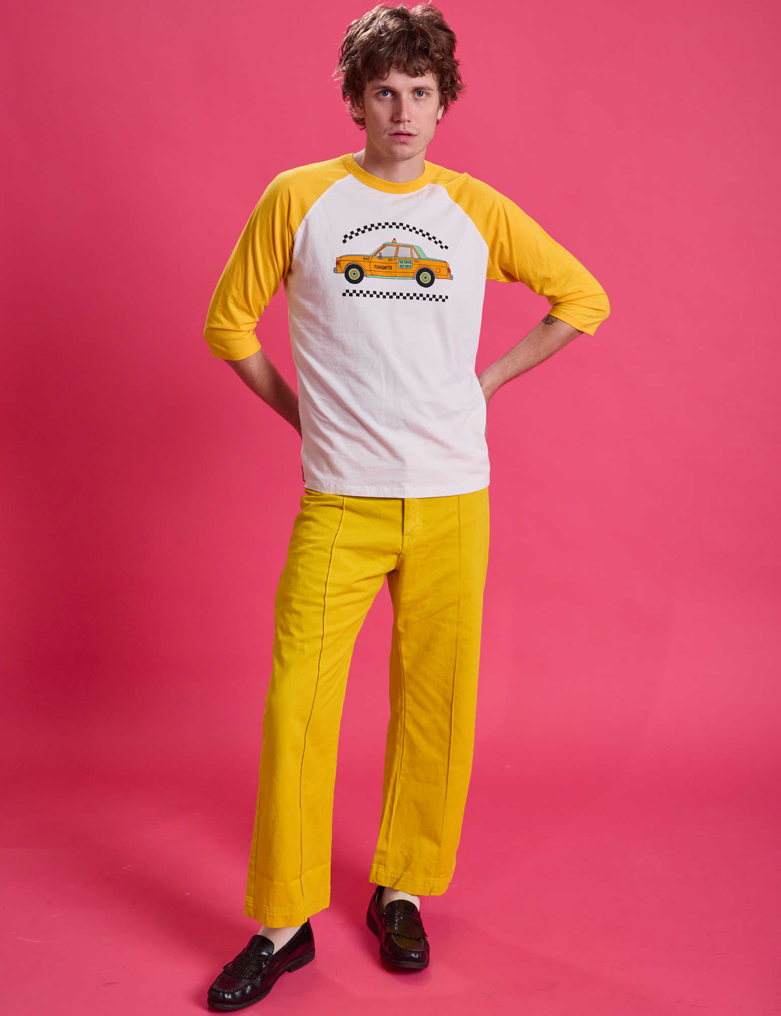 Quinn is wearing Taxi Raglan Tee in Toronto and golden yellow Western Pants