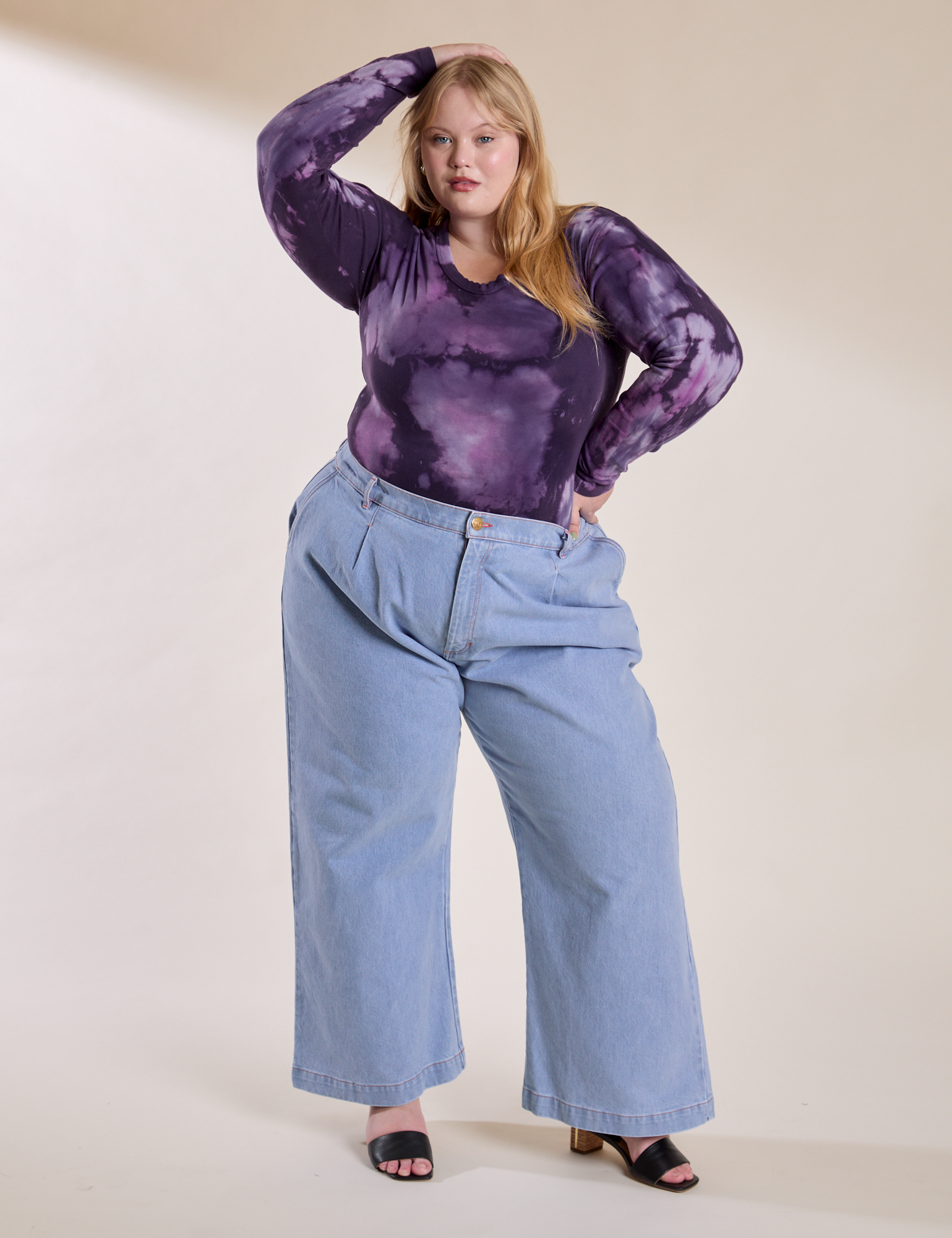 Juliet is wearing Long Sleeve Baby Tee in Dark Lavender tucked into light wash Indigo Wide Leg Trousers