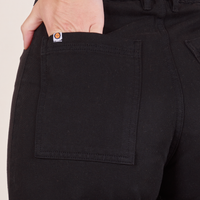Back pocket close up of Western Pants in Basic Black. Alex has her hand in the pocket