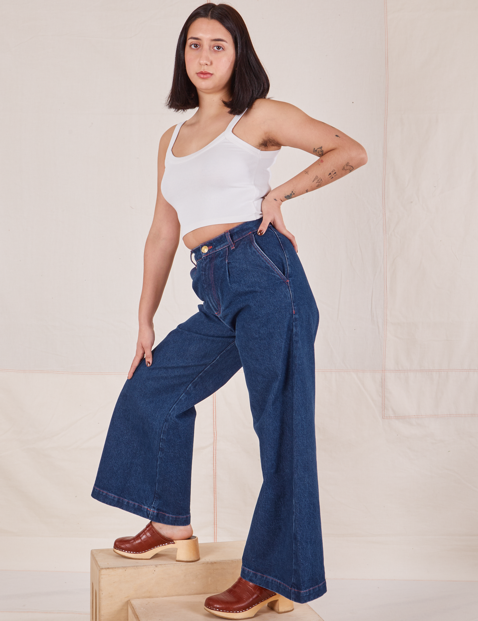 Side view of Indigo Wide Leg Trousers in Dark Wash and vintage off-white Cami on Betty