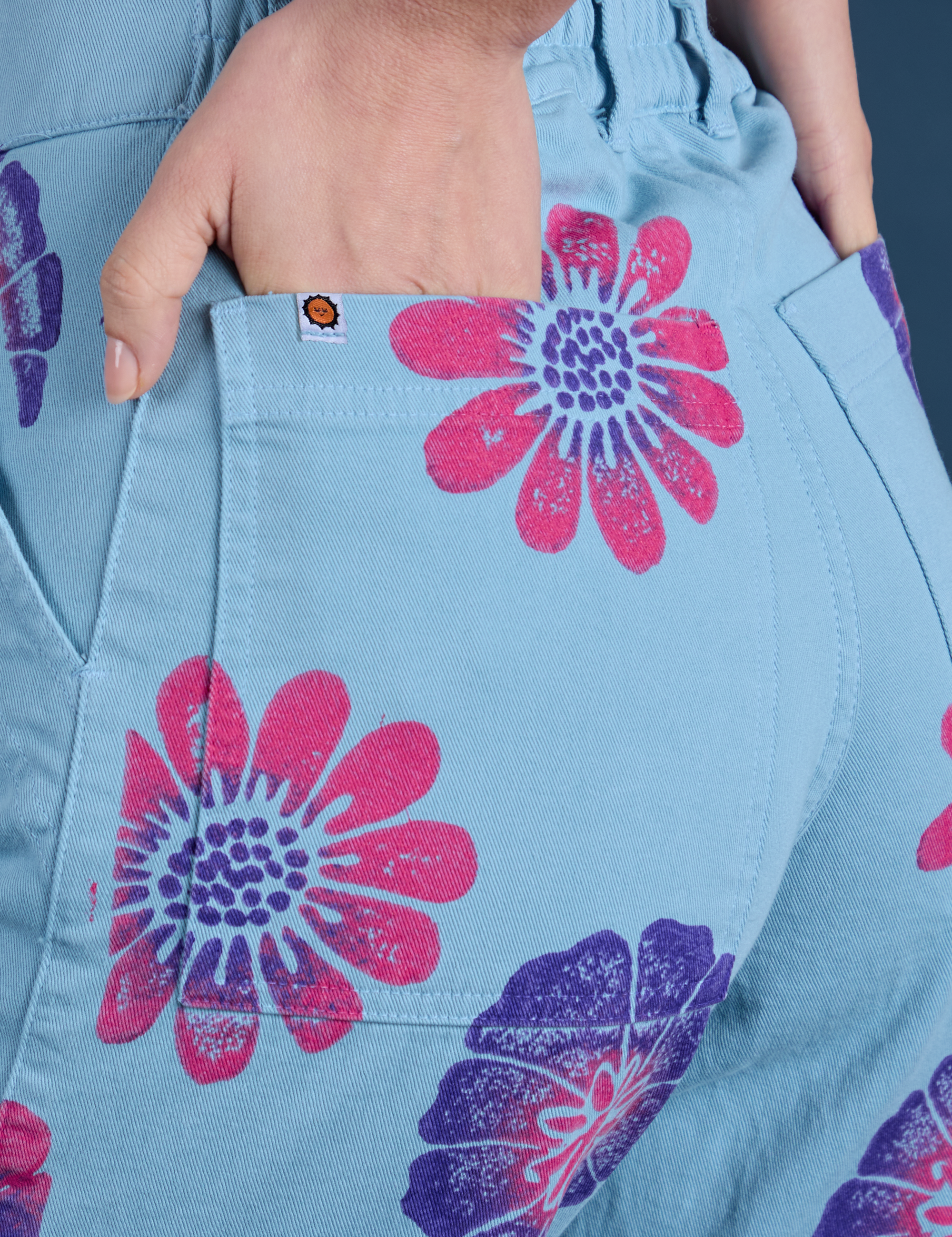 Close up of Madeline's hand in the back pocket of Floral Painted Work Pants in Blue