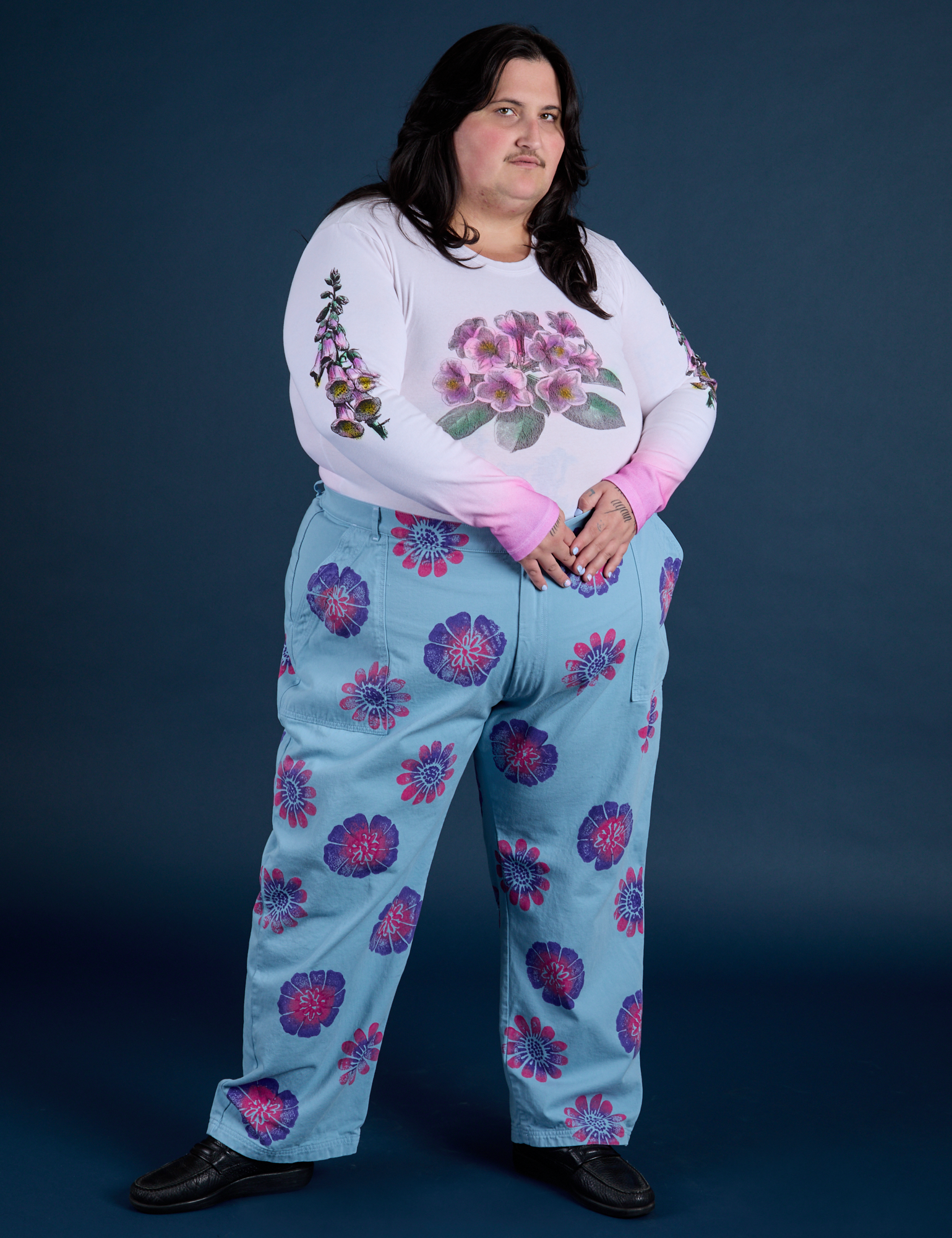 Sam is wearing Floral Long Sleeve Baby Tee in Pink and Floral Painted Work Pants in Blue
