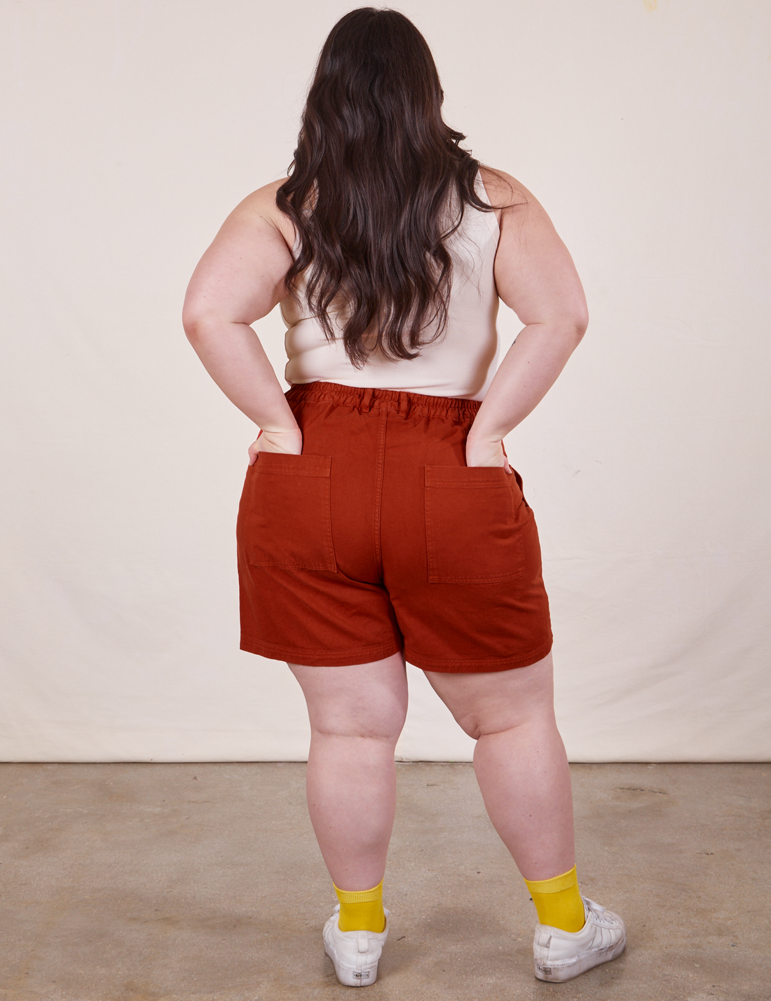 Back view of Classic Work Shorts in Paprika. Ashley has both hands in the pockets.