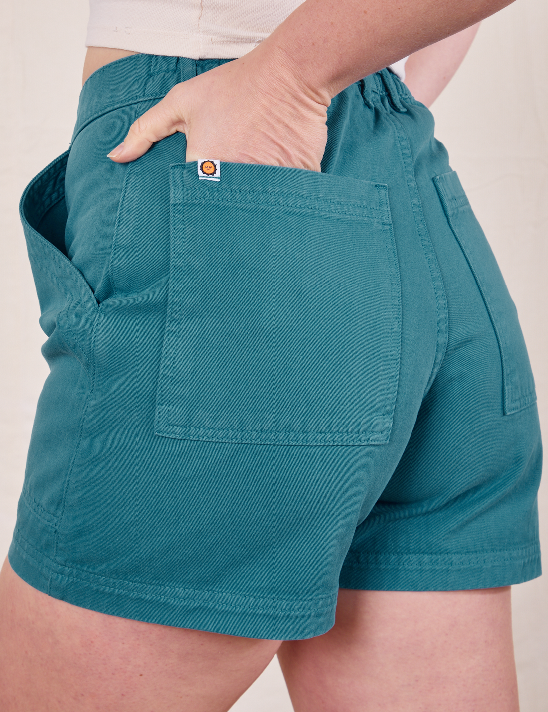 Back pocket close up of Classic Work Shorts in Marine Blue. Allison has her hand in the back pocket.