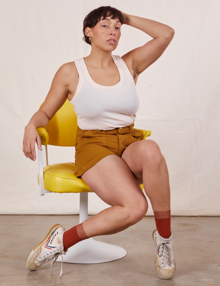 Tiara is sitting in a yellow chair wearing Classic Work Shorts in Spicy Mustard and vintage off-white Tank Top