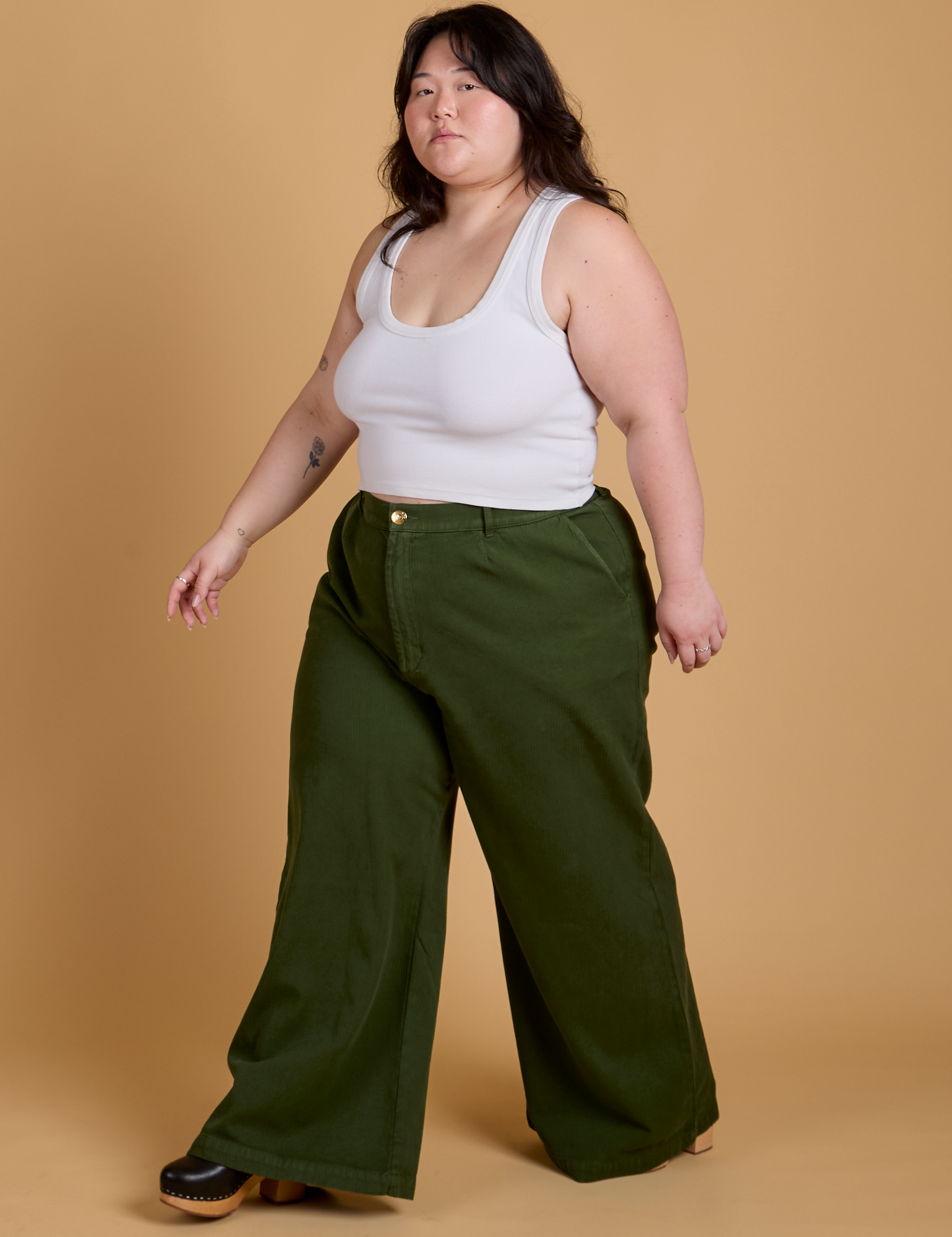 Angled front view of Heritage Wide Leg Trousers in Evergreen and vintage tee white Cropped Tank on Ashley