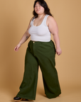 Angled front view of Heritage Wide Leg Trousers in Evergreen and vintage tee white Cropped Tank on Ashley