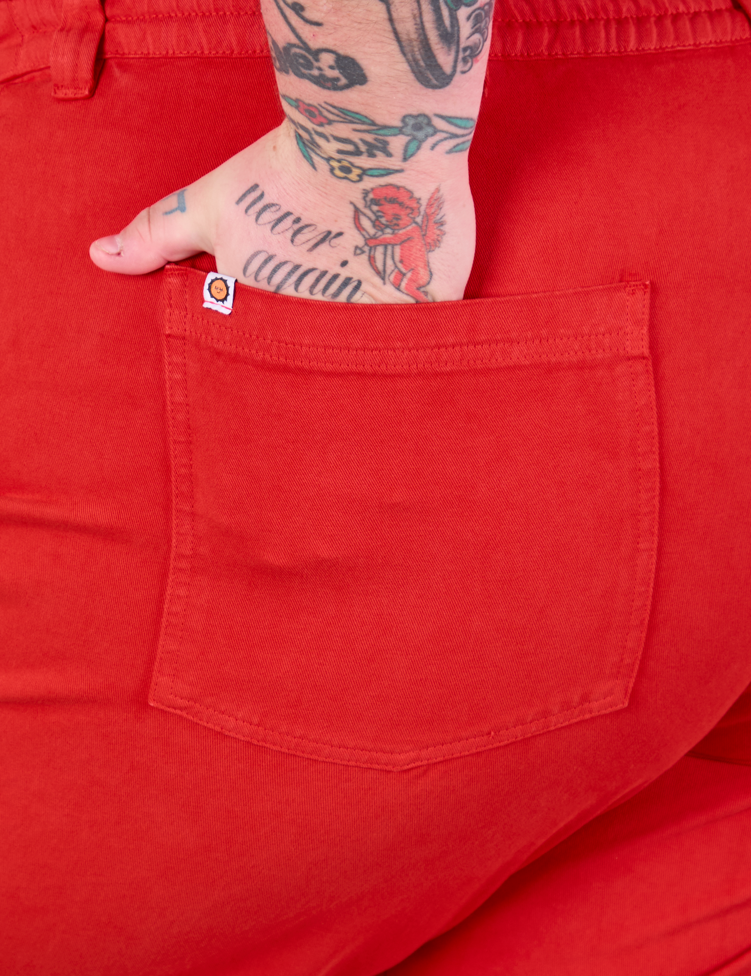 Close up of Sam&#39;s hand in the back pocket of Mid-Rise Work Pants in Mustang Red