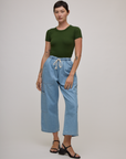 Alex is wearing Baby Tee in Evergreen tucked into light wash denim drop pocket pants