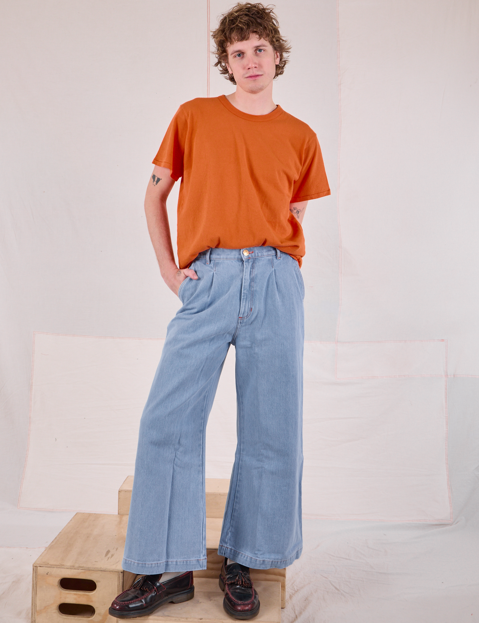 Quinn is wearing Burly Tee in Construction Orange tucked into light wash Denim Wide Leg Trousers