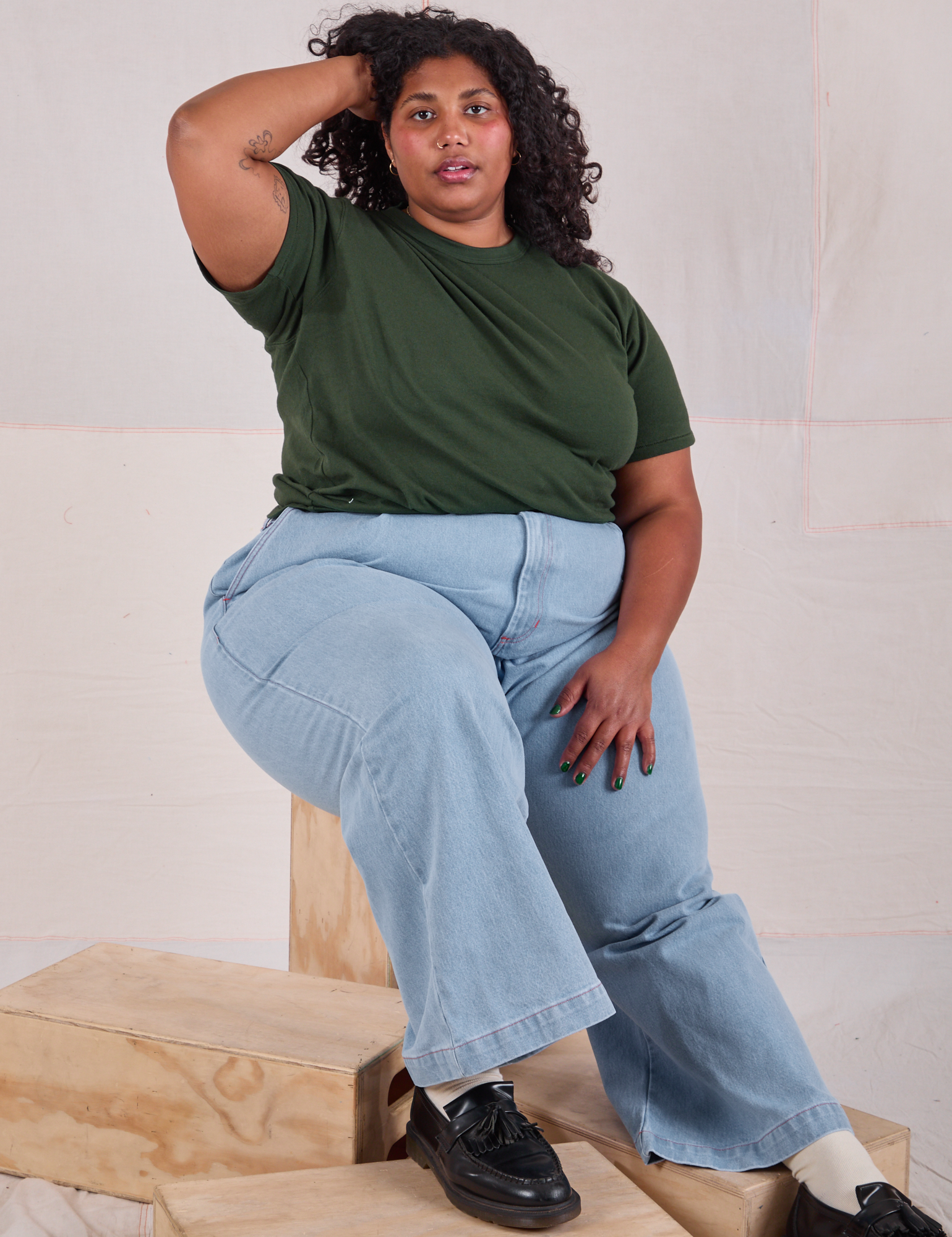 Morgan is wearing Burly Tee in Swamp Green paired with light wash Wide Leg Trousers