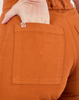 Pencil Pants in Burnt Terracotta back pocket close up. Alex has her hand in the pocket.