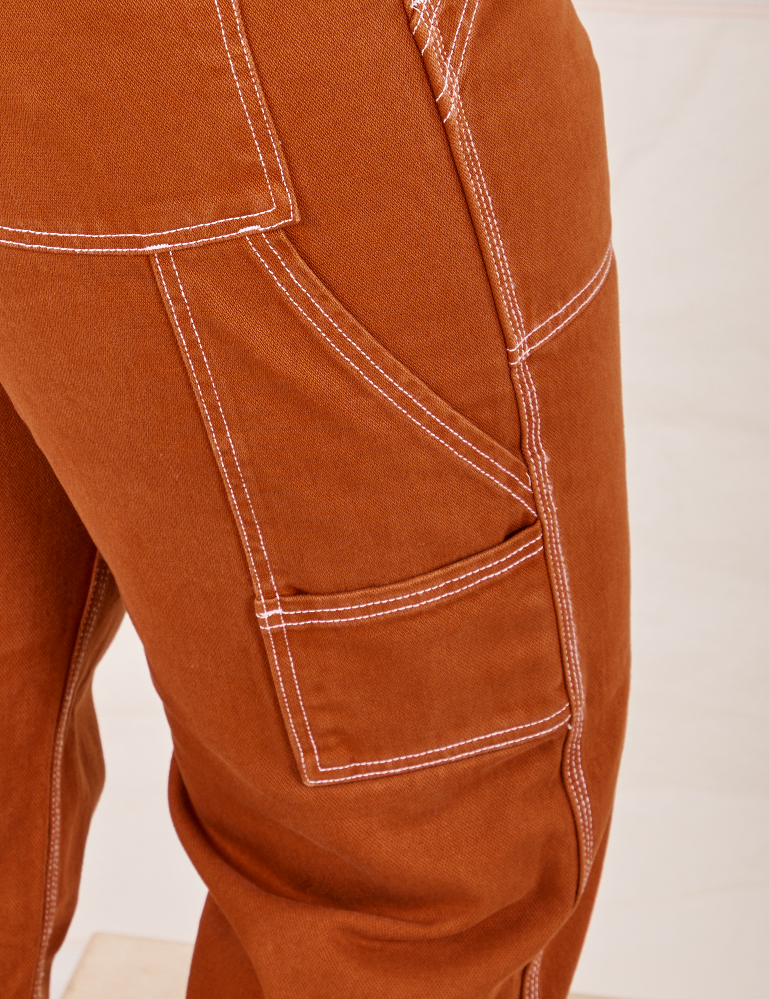 Carpenter Jeans in Burnt Terracotta pocket close up. White contrast top stitching.