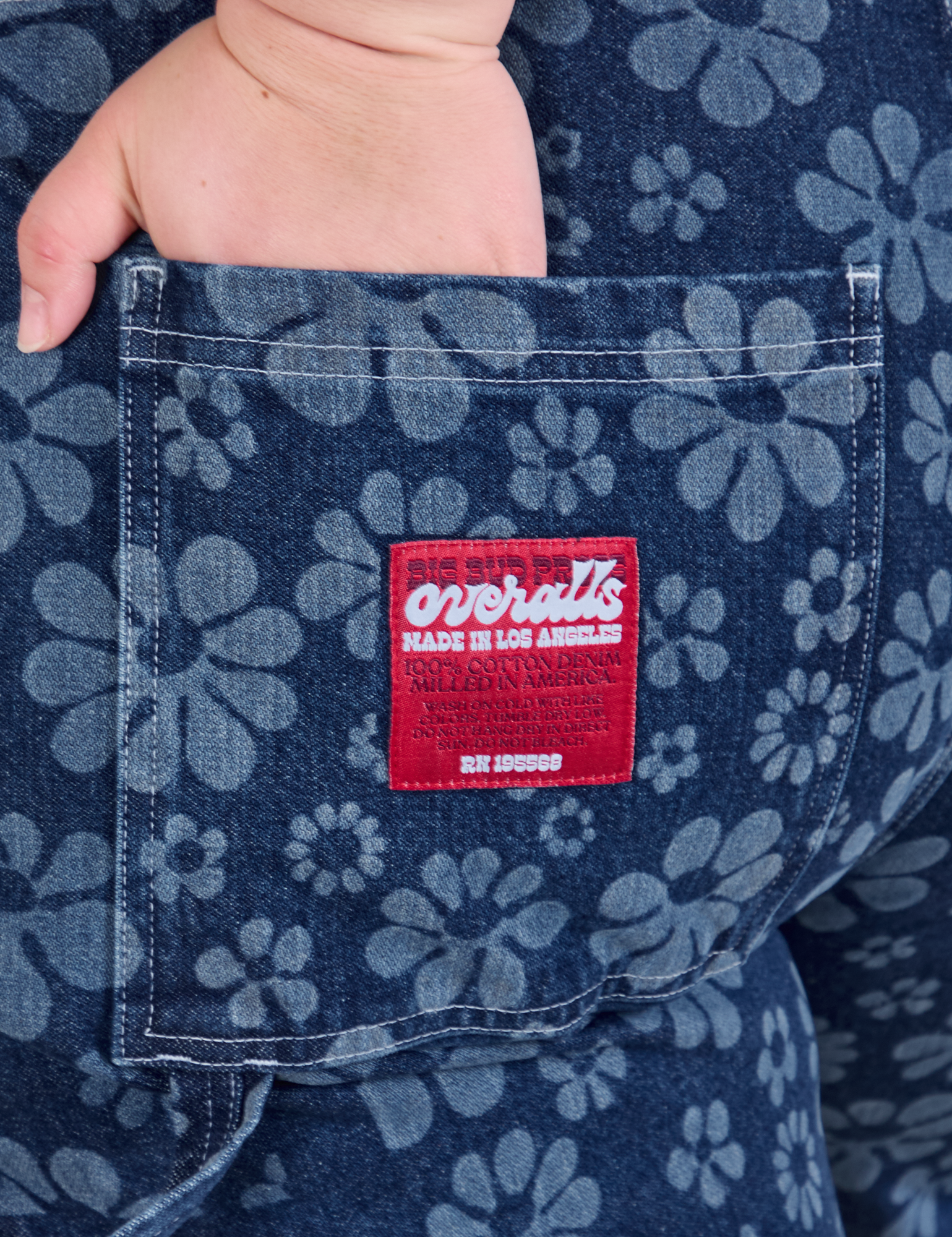 Close up of Ashley&#39;s hand in the back pocket of Carpenter Overalls in Lazy Daisy
