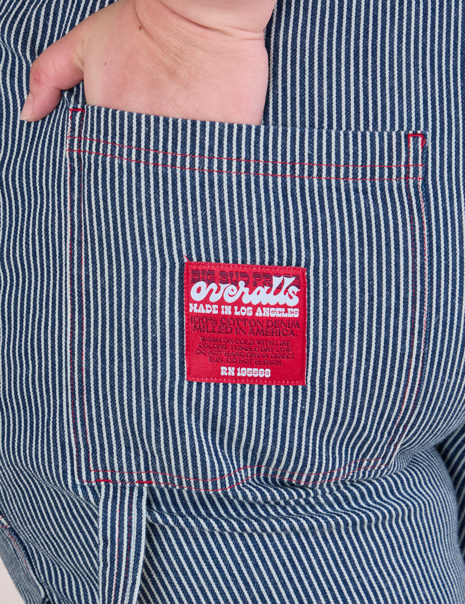 Close up of Ashley&#39;s hand in the back pocket of Carpenter Overalls in Railroad