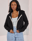 Kandia is 5'3" and wearing P Cropped Zip Hoodie in Basic Black with a vintage off-white Cropped Tank underneath and light wash Carpenter Jeans