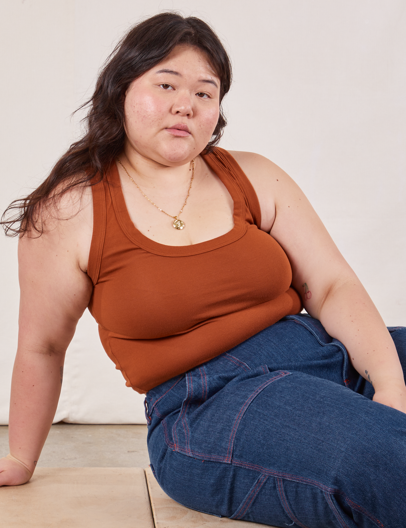 Ashley is wearing Cropped Tank Top in Burnt Terracotta and dark wash Carpenter Jeans