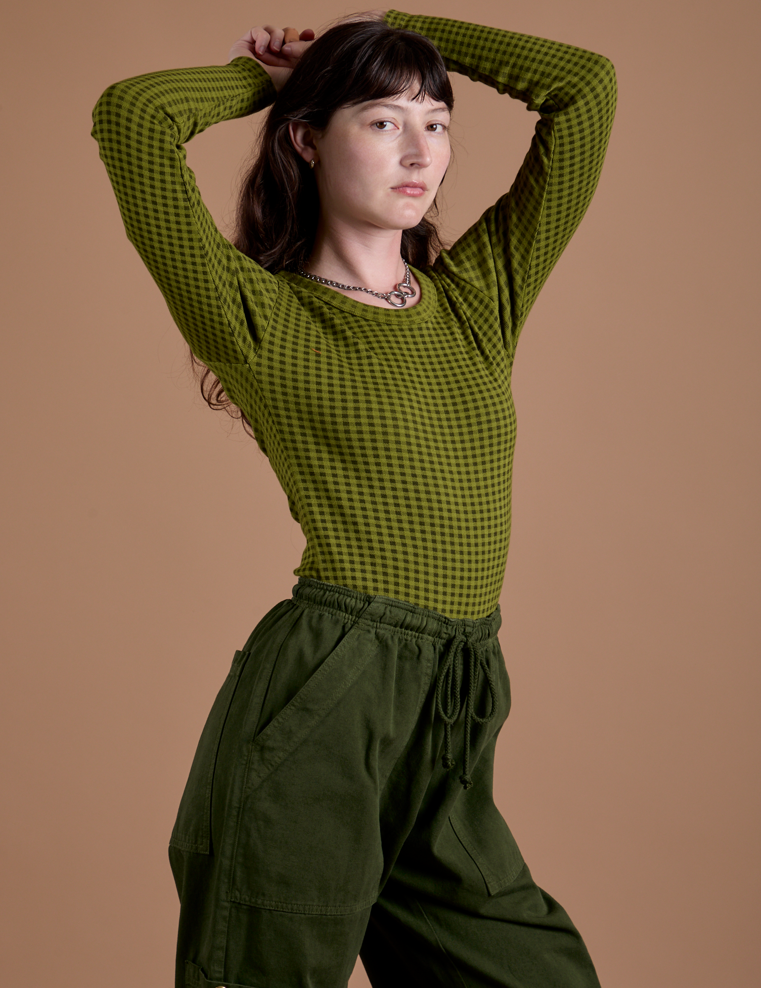 Angled front view of Gingham Long Sleeve Baby Tee in Summer Olive on Alex