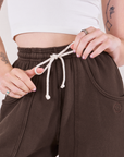 Rolled Cuff Sweat Pants in Espresso Brown front close up. Alex is is holding the drawstring bow loops.