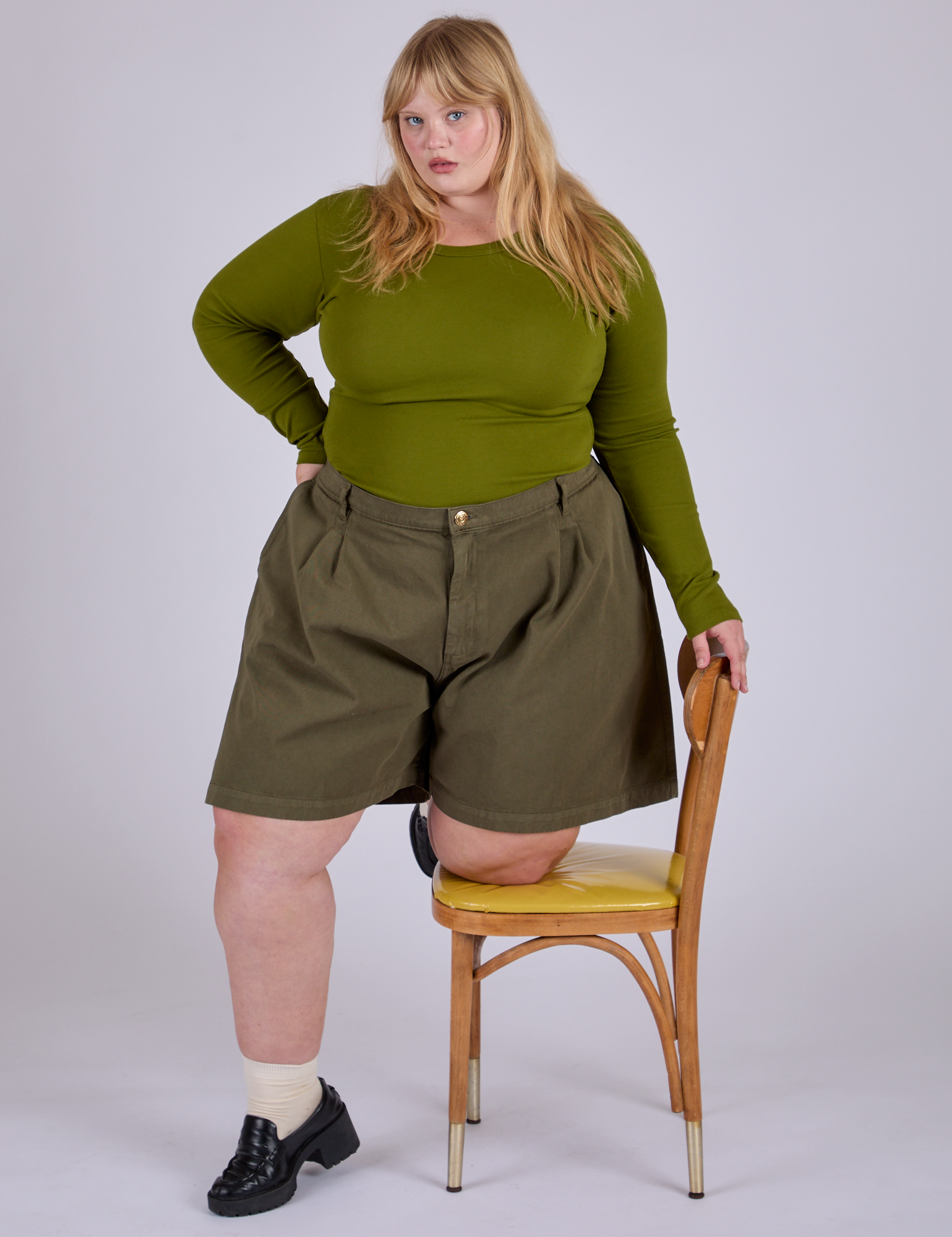 Juliet is wearing Pleated Trouser Shorts in Surplus Green and Long Sleeve Baby Tee in Summer Olive